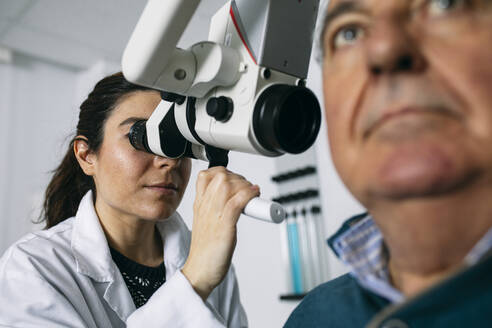 ENT physician examining ear of a senior man - ABZF03030