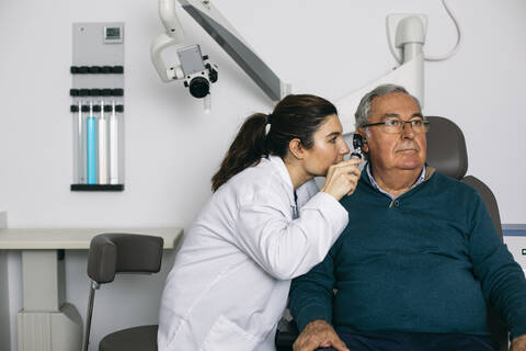 HNO-Arzt untersucht das Ohr eines älteren Mannes mit einem Otoskop, lizenzfreies Stockfoto