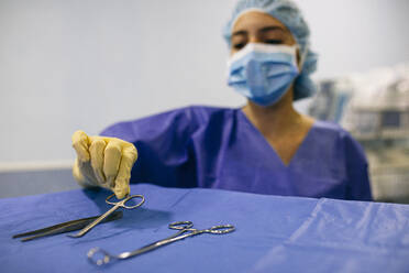 Krankenschwester im Operationssaal nimmt chirurgisches Instrument - ABZF03040