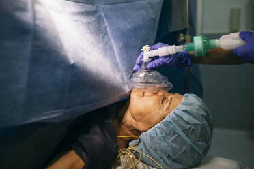 Anesthetist applying anesthesia machine to patient in operating room - ABZF03045