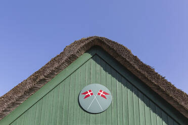 Dänemark, Romo, Dänische Flaggen unter dem Reetdach der Feuerwache gemalt - ASCF01137