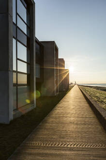 Dänemark, Romo, Uferpromenade entlang einer Reihe von modernen Sommerhäusern bei Sonnenuntergang - ASCF01150