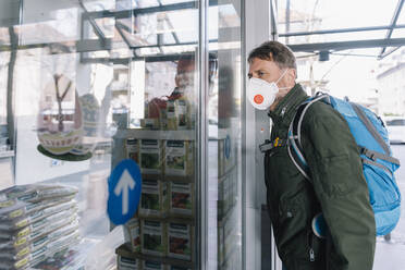 Man with mask looking into supermarket store - MFF05134