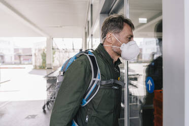 Man with mask looking into supermarket store - MFF05143