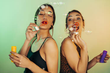 Portrait of two friends blowing soap bubbles - MPPF00693