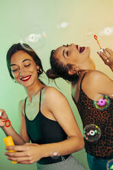 Portrait of two friends having fun with soap bubbles - MPPF00694