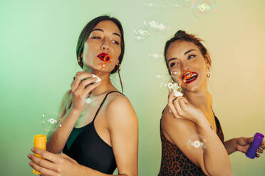 Portrait of two friends blowing soap bubbles - MPPF00695