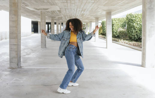 Smiling woman dancing in an empty parking - TCEF00305