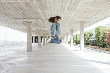 Lächelnde Frau springt in leeres Parkdeck - TCEF00306