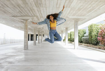 Smiling woman jumping in empty parking deck - TCEF00307