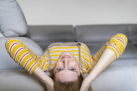 Porträt einer jungen Frau, die zu Hause auf der Couch liegt, lizenzfreies Stockfoto