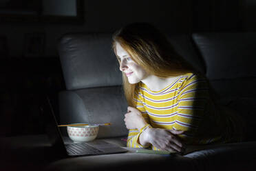 Junge Frau mit einer Laptop-Videokonferenz auf der Couch zu Hause - AFVF05781