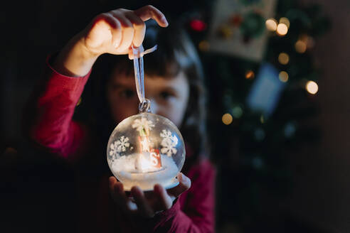 Kleines Mädchen hält beleuchtete Glaskugel zur Weihnachtszeit in den Händen - GEMF03500