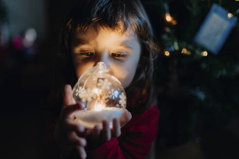 Kleines Mädchen hält beleuchtete Glaskugel zur Weihnachtszeit - GEMF03501