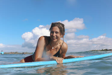 Female surfer lying on surf board, Bali, Indonesia - KNTF04502