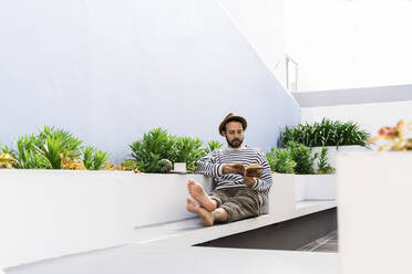 Man sitting on balcony reading a book - AFVF05799