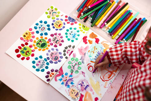Kleines Mädchen zeichnet hässliche Viren mit Farbmarkern zu Hause - GEMF03504