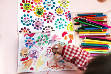 Kleines Mädchen zeichnet hässliche Viren mit Farbmarkern zu Hause - GEMF03505