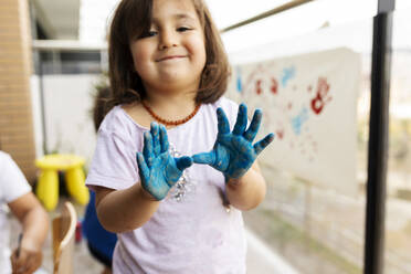 Little girl messing around with her painted hands - VABF02669