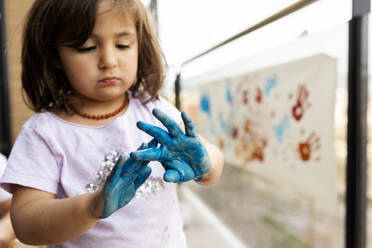 Little girl messing around with her painted hands - VABF02670