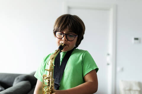 Junge übt zu Hause das Saxophonspielen, lizenzfreies Stockfoto