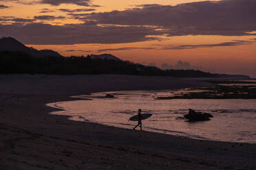 Indonesien, Sumbawa, Silhouette einer Surferin in der späten Abenddämmerung - KNTF04511