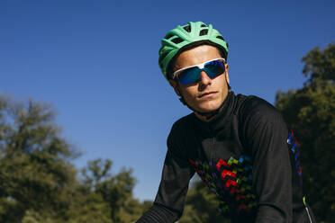 Portrait of confident cyclist under blue sky - ABZF03067
