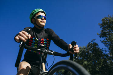 Sportler fährt Fahrrad unter blauem Himmel - ABZF03069
