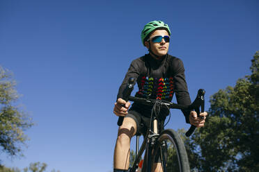 Sportler fährt Fahrrad unter blauem Himmel - ABZF03070
