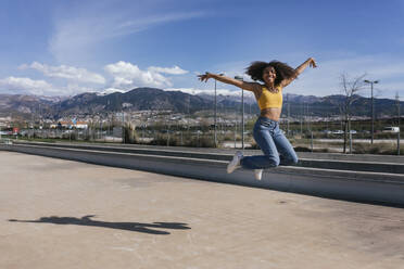 Portrait of happy young woman jumping in the air, Spain - TCEF00313