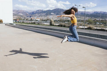 Portrait of happy young woman jumping in the air - TCEF00325