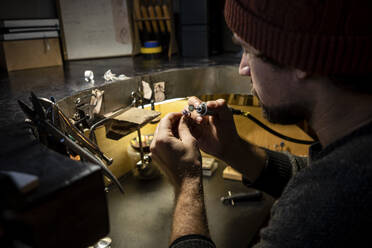 Goldschmied bei der Arbeit an einem Ring in seiner Werkstatt - VPIF02144