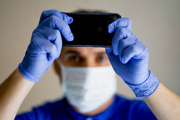 Arzt mit Gesichtsmaske, der ein Smartphone benutzt - CJMF00272