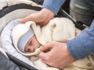 Vater legt sein neugeborenes Kind in den Kinderwagen - LAF02465