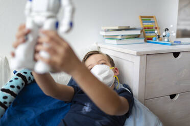 Boy with mask playing in his room during the corona crisis with his new, only friend, a robot - HMEF00823