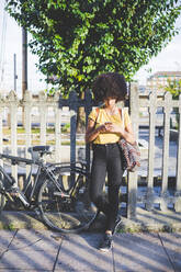 Young woman with afro hairdo using smartphone in the city - MEUF00212