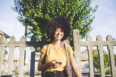 Porträt einer glücklichen jungen Frau mit Afrofrisur in der Stadt - MEUF00213
