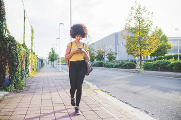 Young woman with afro hairdo using smartphone in the city - MEUF00214