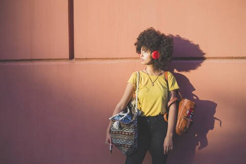 Young woman with afro hairdo listening to music with headphones stock photo