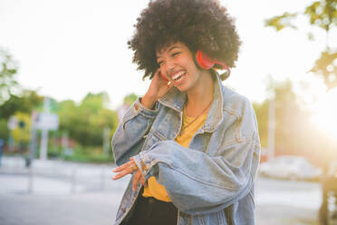 Happy young woman with afro hairdo dancing in the city - MEUF00244