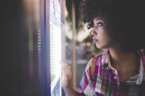 Young woman with afro hairdo using touchscreen vending machine in the city - MEUF00257