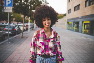 Portrait of smiling young woman with afro hairdo in the city - MEUF00259