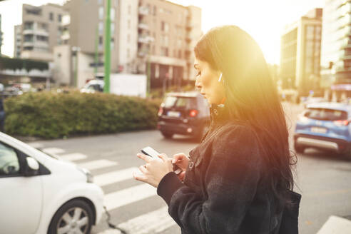 Schöne Frau steht auf einer Straße und benutzt ein Smartphone - MEUF00283