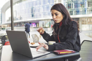 Frau mit Laptop beim Frühstück in einem Cafe - MEUF00287