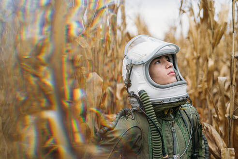 Young spaceman standing in wilted corn field - JCMF00451