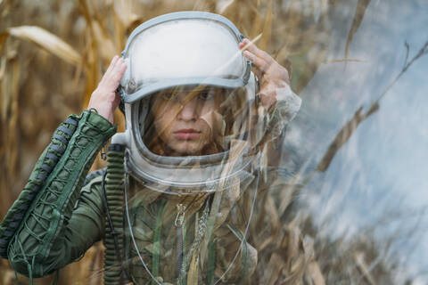 Young spaceman standing in wilted corn field stock photo