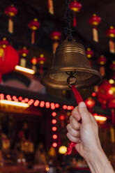 Malaysia, Hand of woman ringing small bell inside temple - JCMF00481