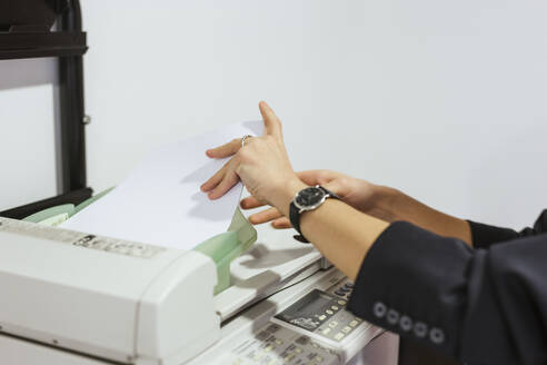 Close-up of businesswoman taking papers from printer in office - LJF01454