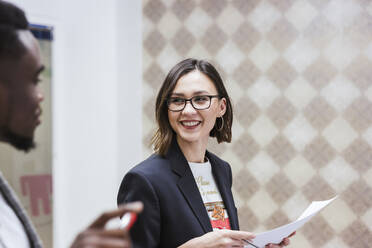 Portrait of young businesswoman holding papers in office - LJF01458