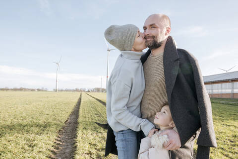 Glückliche Eltern mit kleiner Tochter auf einem Feld im Winter, lizenzfreies Stockfoto